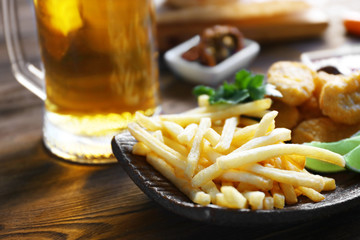 Wall Mural - Glass mug of light beer with French fries on dark wooden table, close up