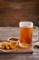 Wall Mural - Glass mug of light beer with snacks on wooden table, close up