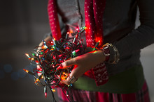 Close Up Of Young Woman Holding Tangle Of Christmas Lights