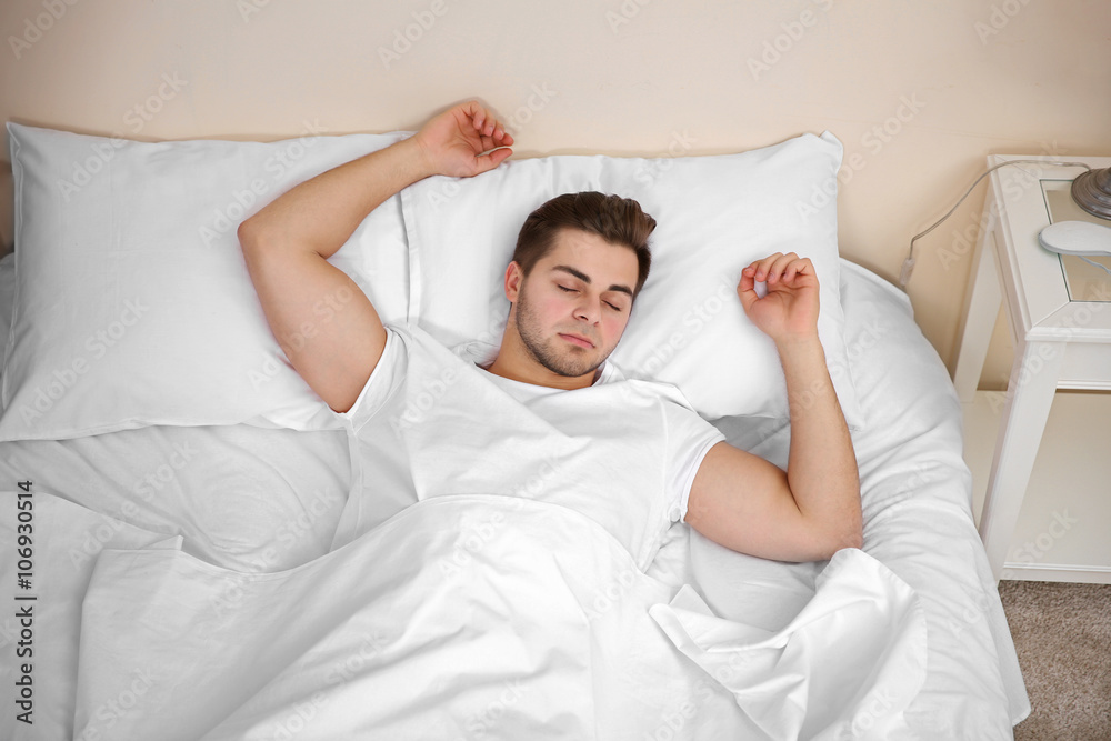 Young man sleeping in bed at home