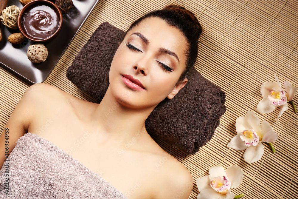 Beautiful young girl lying on massage table in spa salon
