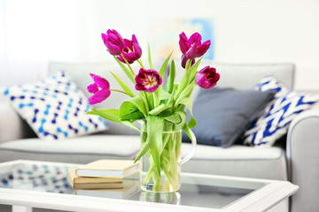 Poster - A bouquet of violet tulips in a vase on white table.