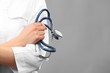 © Africa Studio - Young female doctor with folded arms and stethoscope on grey background