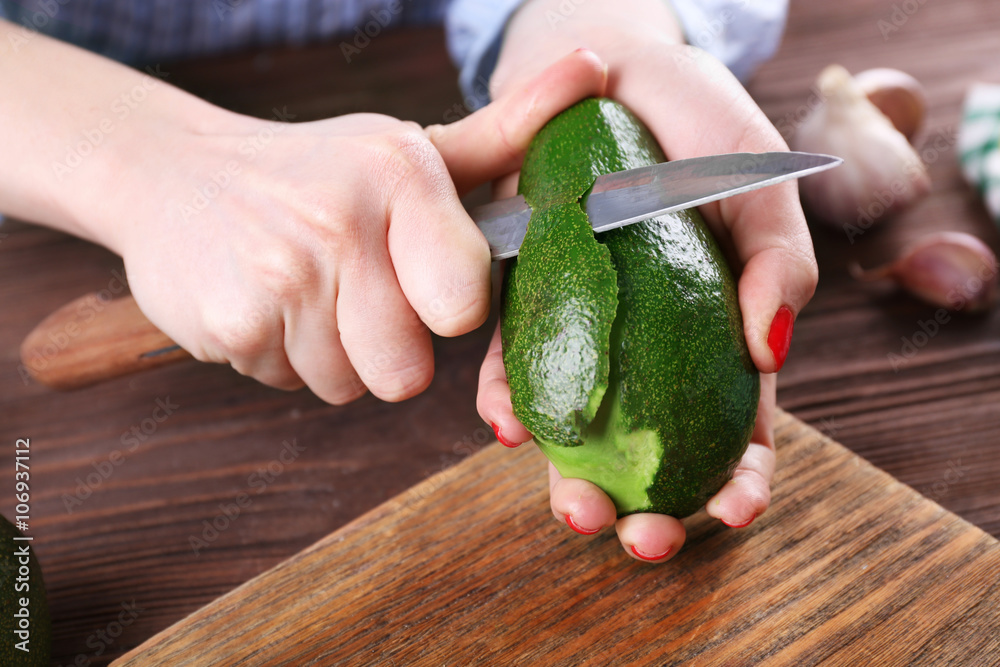 Female hands peeling an avocado, close up