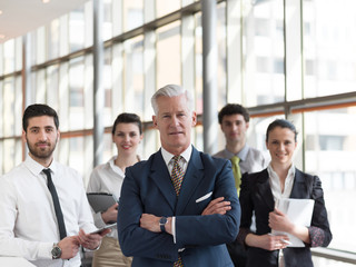 portrait of senior businessman as leader  with staff in backgrou