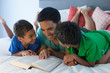 © Connect Images - Father and sons reading on bed