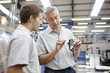 © Connect Images - Manager and working looking at component in engineering factory