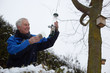 © Connect Images - Senior man filling bird feeders in garden in winter