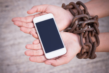 Hands chained holding smartphone.