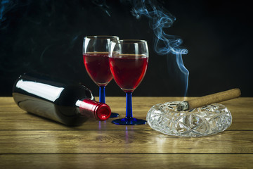 A bottle of wine, a glass and lit a cigar