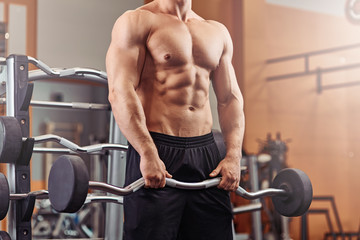 Strong man weightlifting at the gym looking happy and working on his biceps