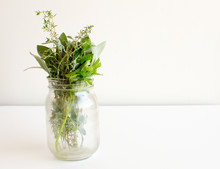 Small Bunch Of Herbs (parsley, Sage, Thyme) In Glass Jar On White Table
