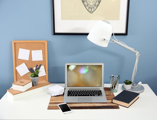 Canvas Print - Workplace with laptop, mobile phone and table on blue wall background