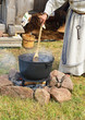 Woman cooks medical drink on a fire