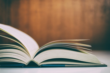 Wall Mural - Close up of open book on desk with vintage filter blur background