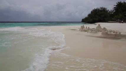 Wall Mural - Maldives, waves on the beach, a little storm and a sand castle on the beach 