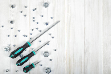 Wall Mural - Top view of nuts and three screwdrivers situated diagonally on wooden DIY workbench