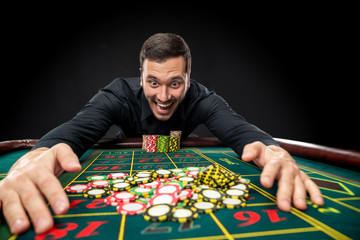 Young handsome man playing roulette wins at the casino