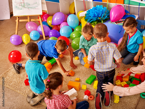 Fototapeta Group children game blocks on floor in kindergarten Balloons on floor Top view