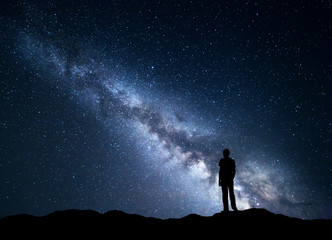 Wall Mural - landscape with blue milky way. night sky with stars and silhouette of a happy man on the mountain. b