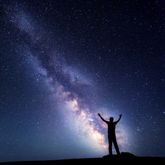 Wall Mural - landscape with colorful milky way. night sky with stars and silhouette of a happy man with raised up
