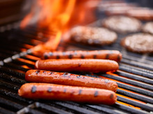 Tasty Hot Dogs Cooking On Grill With Hamburgers