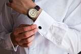 Fototapeta  - Male hands on a background of a white shirt, sleeve shirt with cufflinks and watches, photographed close-up