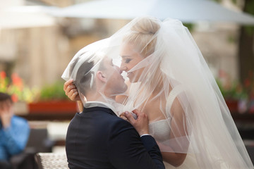 cheerful happy young couple embrace  under a veil on the backgro