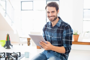 Poster - Portrait of happy man using digital tablet in kitchen