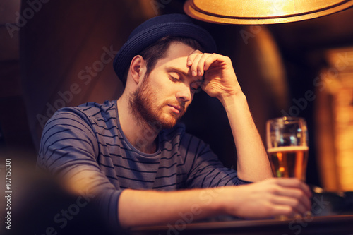 Fotografía unhappy lonely man drinking beer at bar or pub