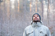 Man breathing deeply in peaceful winter forest on cold day