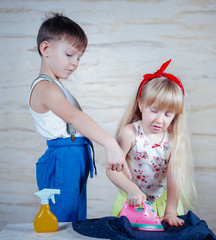 Wall Mural - Young boy supervising a young girl ironing