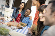 © Mint Images - Men and women seated at a table at a meal.