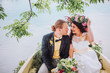 bride and groom sitting in an orange row boat floating out of the tree covering and in to the lake. Bride with wreath of flowers