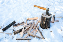 Axe In The Block And Firewood On Snow Background
