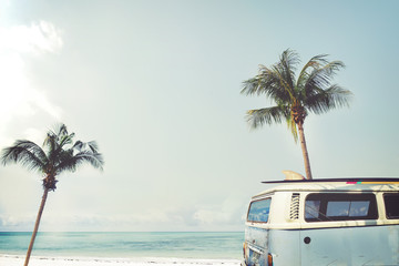 vintage car parked on the tropical beach (seaside) with a surfboard on the roof - leisure trip in th