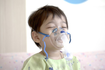 Little boy sick in hospital with a respiratory mask