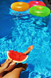 © puhhha - Summer Vacation. Summertime Fun. Female Hand Holding Slice Of Ripe Juicy Watermelon By The Swimming Pool. Colorful Floating Rings In Refreshing Blue Water On Background. Freshness, Enjoyment Concept