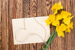 Spring yellow  daffodils  flowers and empty tag on brown painted wooden planks. Selective focus. Place for text.