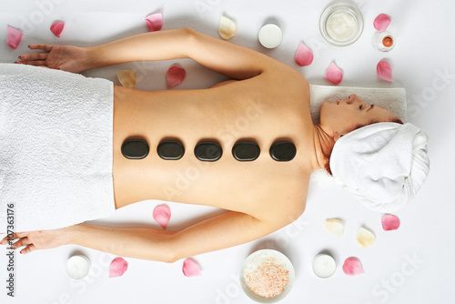 Woman having hot stones on her back in spa salon Plakát
