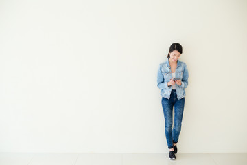 Wall Mural - Woman using cellphone and standing against big wall