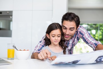 Wall Mural - Father and daughter reading newspaper at home 