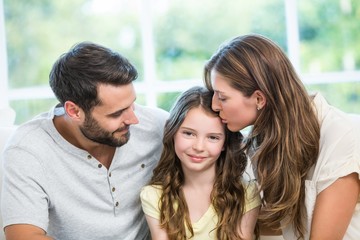 Canvas Print - Mother kissing daughter while father watching them