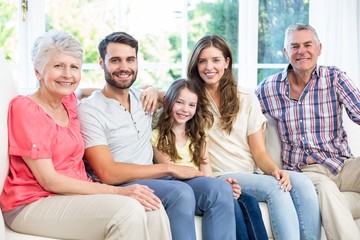 Wall Mural - Portrait of happy family sitting on sofa 