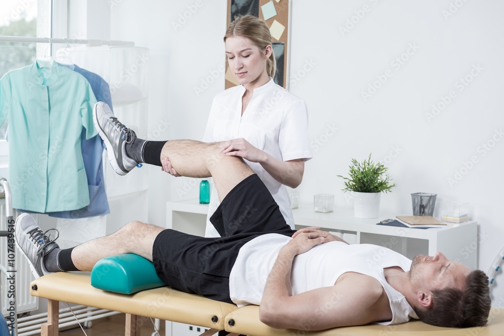 Chiropractor exercising man's leg