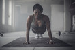© John Fedele/Blend Images - Black woman doing push-ups in dark gym