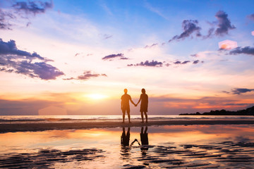 romantic couple on the beach at sunset, silhouettes of man and woman together