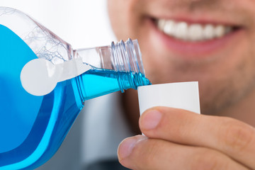 Man Pouring Bottle Of Mouthwash Into Cap