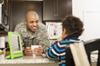 © Roberto Westbrook/Blend Images - Mixed race soldier father and son eating in kitchen