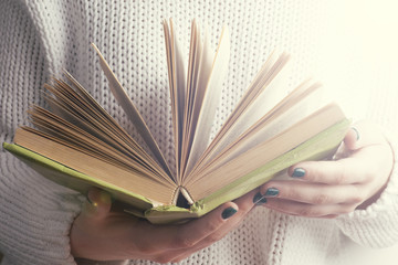 Young girle reading an  open book . old book. Books and reading are essential for self improvement, gaining knowledge and success in our careers, business and personal lives.